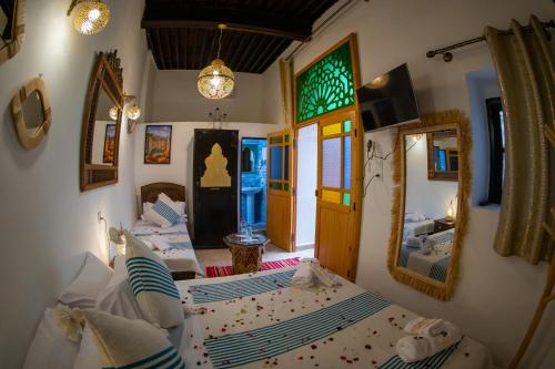 a bedroom with two beds and a mirror at Riad Shauala Fez in Fès