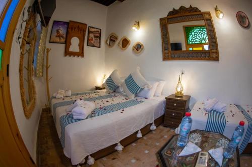 a bedroom with two beds and a mirror at Riad Shauala Fez in Fès