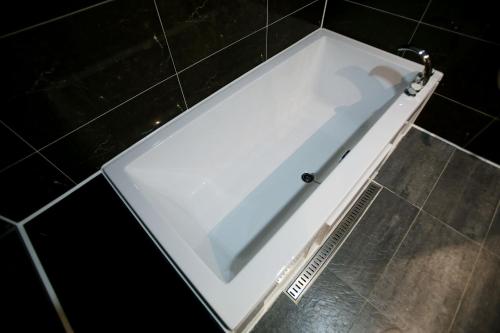 a white bath tub in a black tiled bathroom at Hotel Cullinan Yongin in Yongin