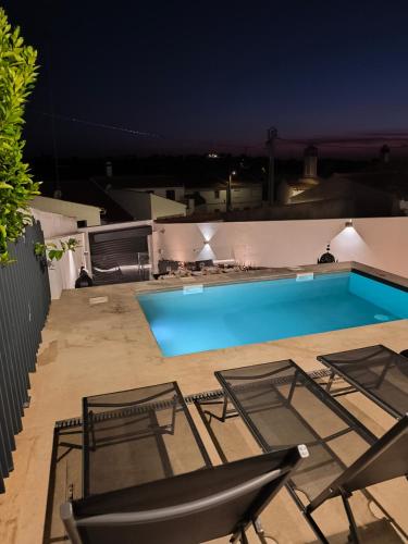 a swimming pool at night with two chairs and a table at VILLA Bléanah in Santo Aleixo