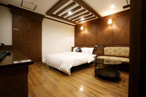 a bedroom with a bed and a table and a couch at Hotel Cullinan Yongin in Yongin