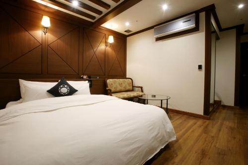 a bedroom with a large white bed and a chair at Hotel Cullinan Yongin in Yongin