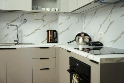 a kitchen with white marble counter tops and a stove at Duo Lux Golem Apartment in Golem