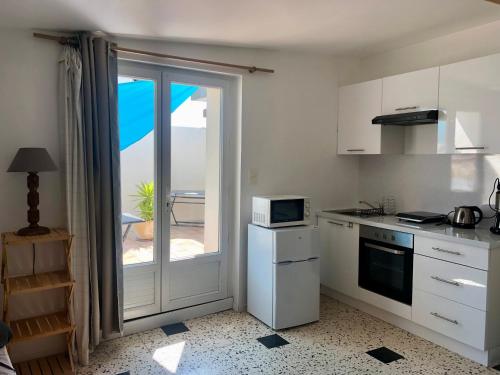 d'une cuisine équipée d'appareils blancs et d'une porte coulissante en verre. dans l'établissement Charmant appartement en duplex & terrasse vue Larzac, à Saint-Jean-de-la-Blaquière