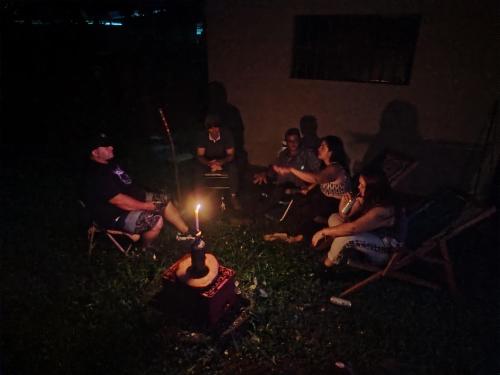 a group of people sitting around a cake with a candle at Casa Club Bluaska in Sarapiquí