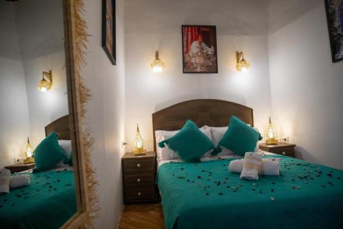 a bedroom with a bed with green sheets and a mirror at Riad Shauala Fez in Fès