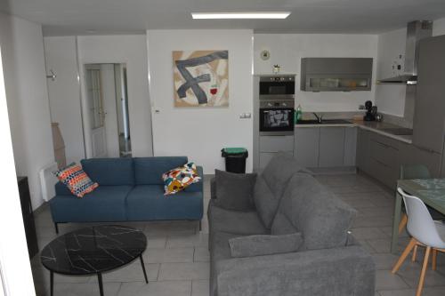 un salon avec un canapé bleu et une cuisine dans l'établissement JOLI T3 MARSEILLE au calme, à Marseille
