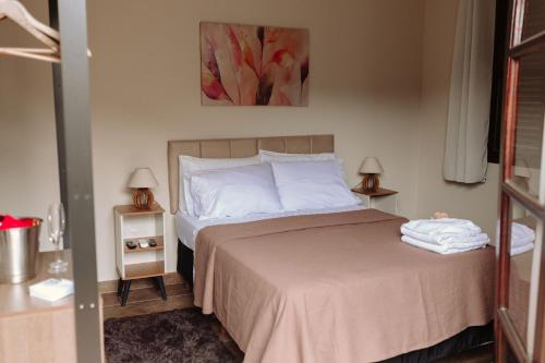 a bedroom with a bed with white sheets and two lamps at Casa da Coruja in Rio de Janeiro