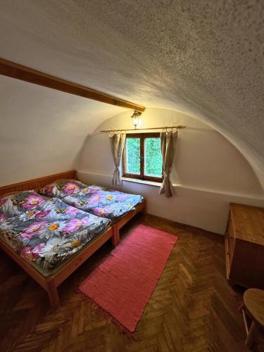 a bedroom with a bed in a room with a window at Chalúpka pod orechom in Liptovský Trnovec