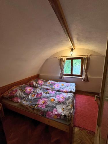 a bed in a small room with a window at Chalúpka pod orechom in Liptovský Trnovec