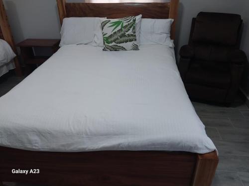 a bed with white sheets and a pillow on it at Casa Honey in Bajo Boquete