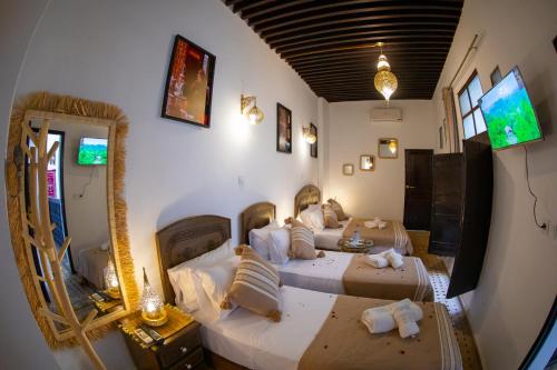 a bedroom with two beds and a mirror at Riad Shauala Fez in Fès