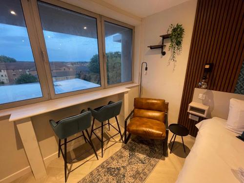 a bedroom with a bed and chairs and a window at CoStays Aparthotel - Middlesbrough in Middlesbrough
