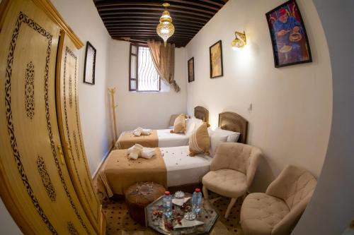 a bedroom with two beds and a table and chairs at Riad Shauala Fez in Fès