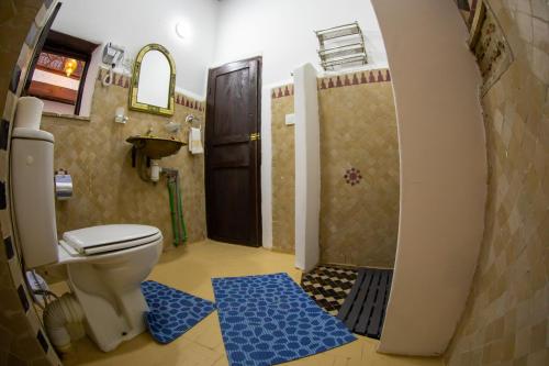 a bathroom with a toilet and a shower with blue rugs at Riad Shauala Fez in Fès