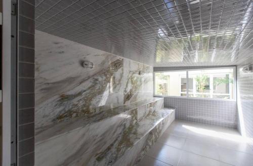 a bathroom with a large marble shower with a window at Almaré Home in Ubatuba