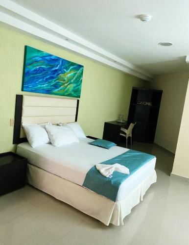 a bedroom with a bed with a painting on the wall at Hotel Aventura suite in Boca de Aroa