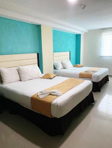 two beds in a room with blue walls at Hotel Aventura suite in Boca de Aroa