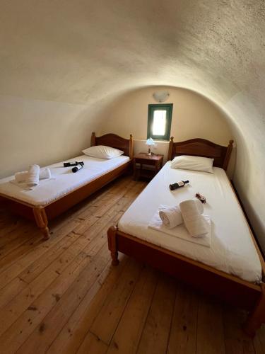 two twin beds in a room with wooden floors at Santa Magia in Kamari
