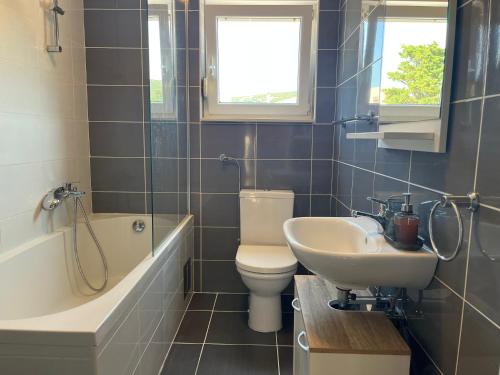 a bathroom with a sink and a toilet and a bath tub at Ventana Pool Apartments - Stara Novalja in Stara Novalja