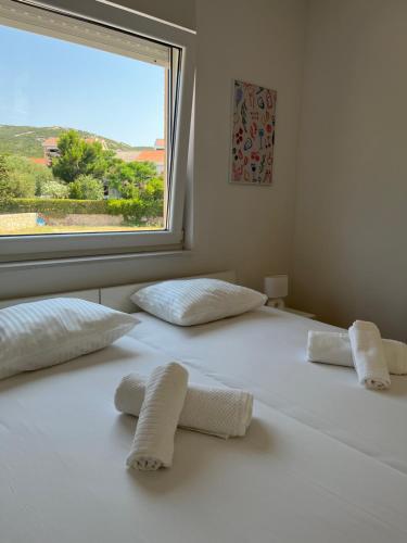 a white bed with two pillows and a window at Ventana Pool Apartments - Stara Novalja in Stara Novalja