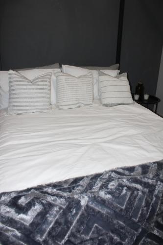 un letto con lenzuola bianche e cuscini sopra di The Alcove Rivonia a Johannesburg