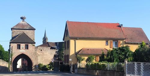 an old building with a tower and a church at Le p'tit coin de chez nous in Dambach-la-Ville