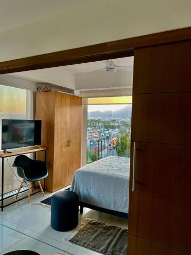 a bedroom with a bed and a view of a city at Chic 1BR 1BA Zoho Skies condo with rooftop pool stunning views in Puerto Vallarta