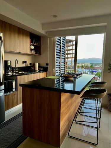 a kitchen with a large island with black counter top at Chic 1BR 1BA Zoho Skies condo with rooftop pool stunning views in Puerto Vallarta