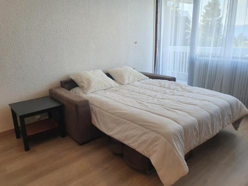 a bed in a bedroom with a table and a window at Spacieux et confortable avec piscine in Chamrousse