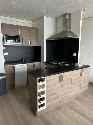 a kitchen with a black counter top and wooden cabinets at Spacieux et confortable avec piscine in Chamrousse