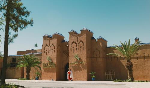 a building in the desert with palm trees at RS Hotel Karam Palace in Ouarzazate