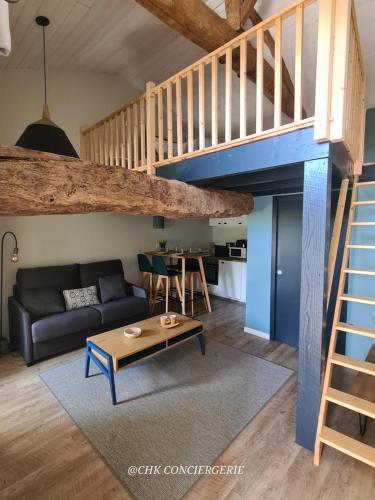 ein Wohnzimmer mit einem Sofa und einem Loft in der Unterkunft Cottage Authentique avec Mezzanine proche du Puy duFou in LʼÉpaux