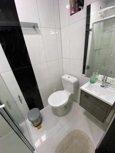 a white bathroom with a toilet and a sink at Apartamento em Guarapuava in Guarapuava