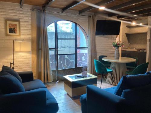 a living room with blue couches and a table and a window at Suites Portal San Ángel I Hospedaje Ejecutivo in Mexico City