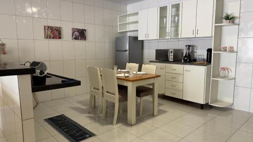 a kitchen with a table and chairs and a refrigerator at Casa moderna e mobiliada n1 com 4 camas e 2 quartos Doce refúgio in Juazeiro do Norte