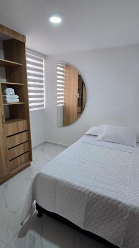 a white bedroom with a bed and a mirror at Apartamento independiente torres de siena pitalito in Pitalito
