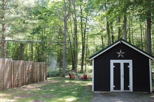 a black shed with a white door and a fence at Lake Huron Lady of the Lake Cabin w HotTub, Sauna in Greenbush