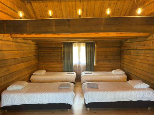 four beds in a room with wooden walls at Privaatne maja metsas, kraanist voolab allikavesi in Plaani