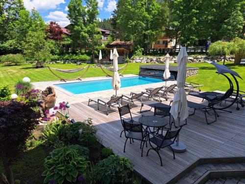 a patio with chairs and umbrellas next to a pool at Landhaus Flasch in Wagrain