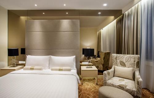 a hotel room with a large bed and a chair at Menara Peninsula Hotel in Jakarta