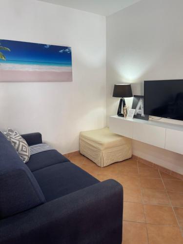 un salon avec un canapé bleu et une télévision dans l'établissement Design apartments - P, à Siniscola