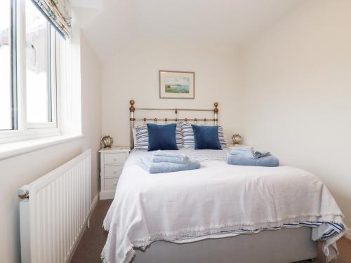 ein weißes Schlafzimmer mit einem großen Bett mit blauen Kissen in der Unterkunft Gull Cottage in Padstow