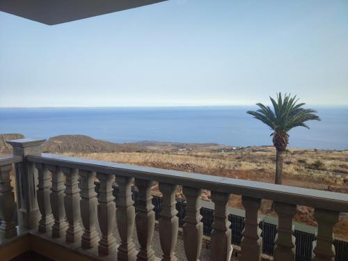 a balcony with a palm tree and the ocean at Villa las Cruces in Alajeró