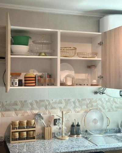 a kitchen with white cabinets and a counter with dishes at Karim Palace ,Five Stars Quality With Low Budget, Near The Beach And Airport in Tangier
