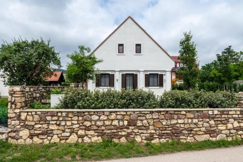 a white house behind a stone wall at Viktória Kőház Köveskál in Köveskál