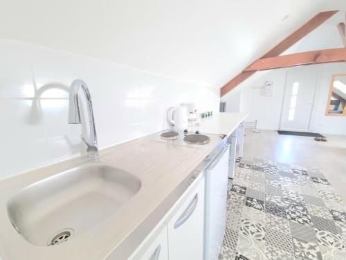 Il comprend une cuisine blanche avec un évier et du carrelage. dans l'établissement Appartement, proche Gare et Centre-Ville, à Blois