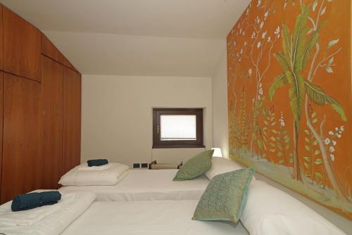 two beds in a room with a painting on the wall at Peschieraloft in Peschiera del Garda
