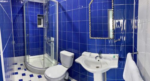 Un baño con azulejos azules, inodoro y lavabo. en Aeroport Rooms, en Chişinău