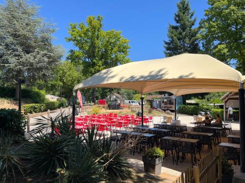un gruppo di tavoli e sedie sotto un ombrellone di Mobil home tout confort a Saint-Chéron